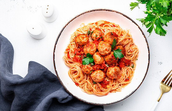Cooked Spaghetti Pasta With Meatballs And Spicy Tomato Sauce With Parsley In Plate, White Table Background, Top View