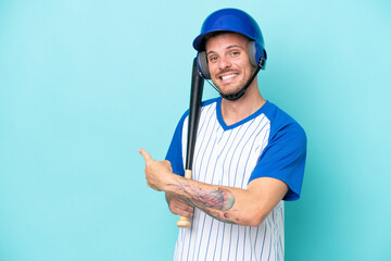 Baseball player with helmet and bat isolated on blue background pointing back