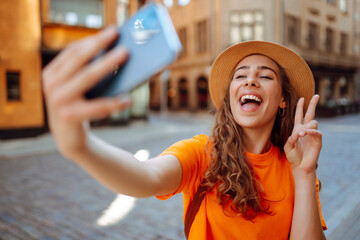 Selfie time. A tourist walks the streets and  takes selfie using smartphone camera.   Lifestyle,...