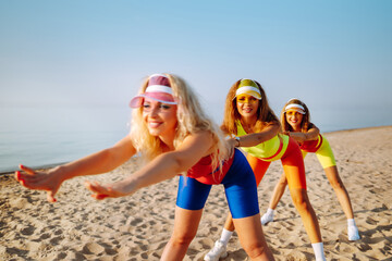 Dancing on the beach. Young woman in colorful swimsuits are dancing in the morning. Сoncept of sports, fitness, aerobics. Active sport.