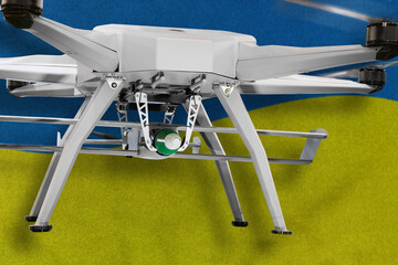 Military drone armed with bomb on a background of Ukrainian flag.