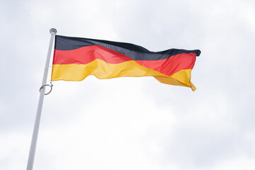 German flag flutters in the wind. State symbol of Federal Republic of Germany. 