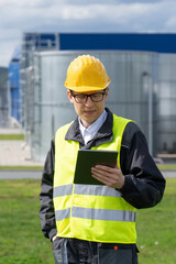 Engineer with digital tablet on a background of gas tanks.	