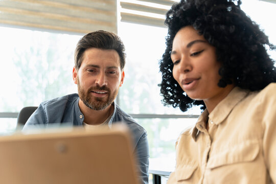 Diverse colleagues analyze charts with quarterly reports, read contract from investors in the office
