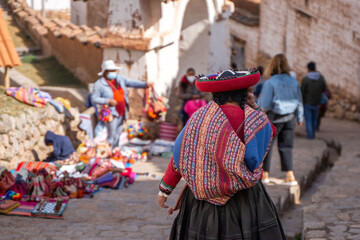 Rear view of peruvian indigenous woman dressed in traditional colorful clothes - obrazy, fototapety, plakaty