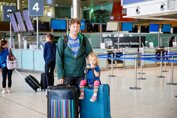 Cute little toddler girl and father at the airport. Happy family traveling by plane, making vacations. Young dad and baby daughter with suitcases waiting for flight. Family going on journey. Ireland