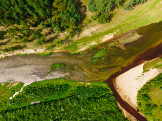 Beautiful river meandering between forest and field. Aerial view. Juicy view green forest and plants.