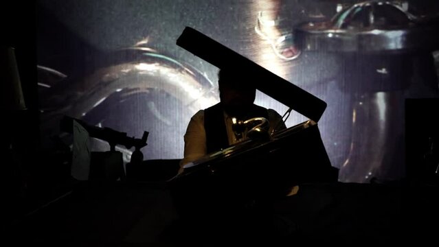 A vintage mechanical gramophone plays a vinyl record. a man in the twilight on the table turns a vintage gramophone. Half-light, with a video sequence in the background. High quality FullHD footage