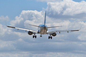 Commercial airplane making a descent on landing with stormy clouds at noon