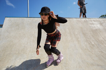Cool young roller blader female skating in a concrete skate pool in a sunny summer day. Aggressive...