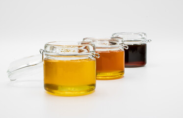 Jars with three different types of honey isolated on a white background - Powered by Adobe