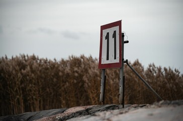 Sign saying 11 near the shore on a cloudy day.