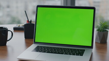 Modern green screen laptop standing on office desk close up. Chroma key computer