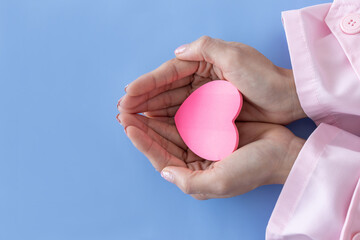 Heart in Doctor's hands on blue background. A Doctor's hand protecting and reassures patient.Healthcare and hospital medical. Organ donation,charity,cardiologist,heart care .Valentine day.copy space..