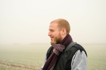 Closeup of a male with a warm scarf in the cloudy sky in the background