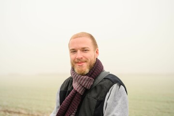 Closeup of a male with a warm scarf in the cloudy sky in the background