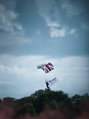 Lover of extreme sports skydiving with a parachute with the UK flag from the cloudy sky