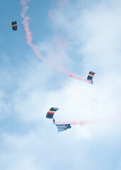 Vertical of skydivers diving with a parachute from the cloudy sky