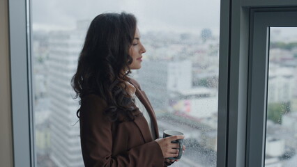 Fototapeta premium Closeup woman drinking coffee looking on city from office window. Girl resting.