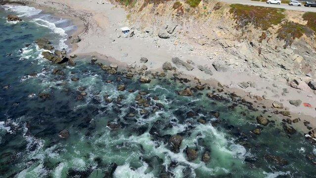 Beautiful drone footage of a calm sunny day at the sea surrounded by rocks