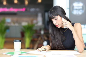 Portrait of confident African businesswoman with happy smiling emotion drinking coffee while sitting and using smart mobile phone and tablet on table in restaurant. Success business concept