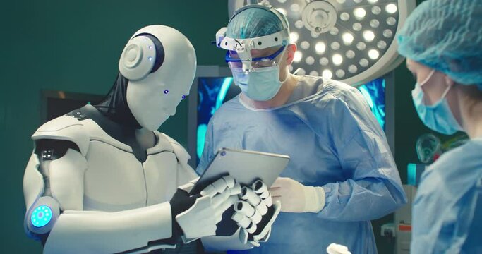 Robot holding digital tablet helps doctor to perform surgical operation in modern hospital. Teamwork of professional medical surgeons in operating room. Concept of modern medicine.