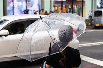 Woman with umbrella waits at the street to cross