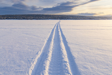 Long trail on a frozen lake towards a forest on a hill in Lapland, Finland