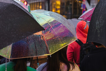 people with umbrellas waiting at a street in the rainy city