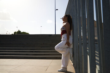 Young latin woman leaning on steel fence. The woman is a dancer of modern dance. Concept youth and...