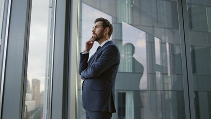 Serious entrepreneur lost thoughts searching problem solution at office window.