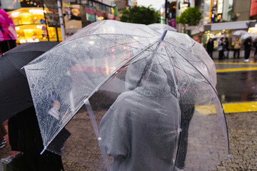 people with umbrellas waiting at a street in the rainy city