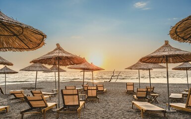 Sunbeds and parasols on beach in Sarande, Albania during sunset afternoon