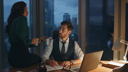 Colleague bringing tea man executive manager working at office desk late evening