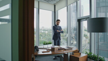 Business man thinking deal standing in office with crossing hands looking window