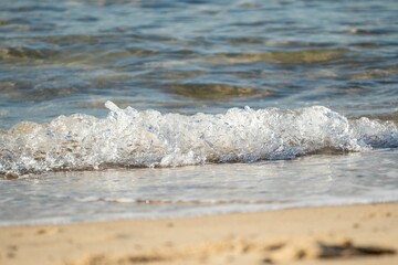 Closeup shot of small waves crashing on the sand at the beach in Australia