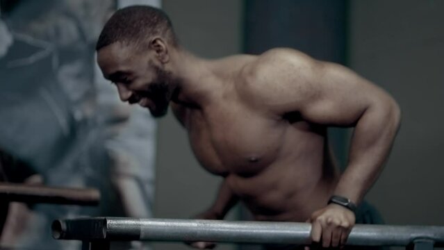 Athletic African American man smiling while warming up for dips