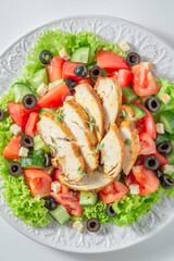 Healthy and classic Caesar salad with chicken, lettuce and tomatoes.