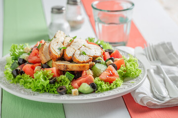 Healthy and classic Caesar salad with cucumber, chicken and tomatoes.