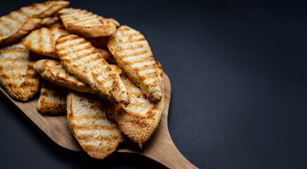 Toasted french baguette for bruschettas sliced on wooden board with copy space closeup. Rustic crusty cutout bread for teraditional snacks