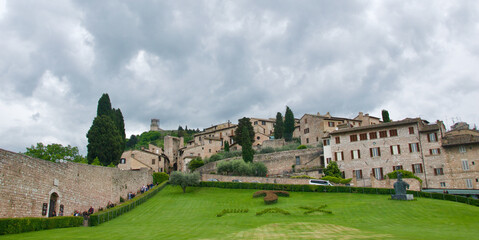 Fototapeta na wymiar Medieval buildings with trees and lawn in Assisi, Italy