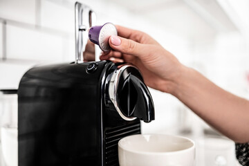Girl hand put capsule to coffee machine at home closeup. Woman preparing italian caffeine beverage...