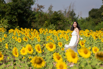 Obraz na płótnie Canvas Female tourist feel happy and chilling among sunflowers garden at Thailand