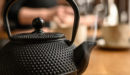 Black metal teapot with hot tea at the kitchen. Tea drinking traditions. Girl making a tea.