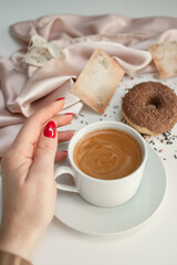 Close-up of a cup of coffee held by a woman's hand.