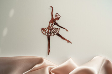 Paper pink ballerina performing a pirouette on a background of pink draped fabric.