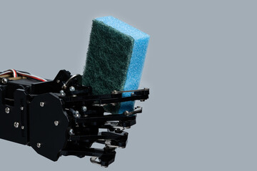 Real robot's hand holding sponge for dishwashing against gray background