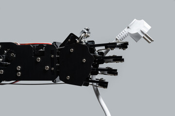 Real robotic hand with power plug. Concepts of AI takeover and Technological singularity