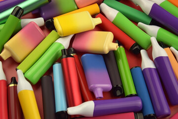 Set of multicolor disposable electronic cigarettes on a red background.