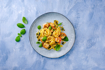 Traditional Italian tagliatelle ai gamberoni pasta with king prawns and herbs served as top view on...